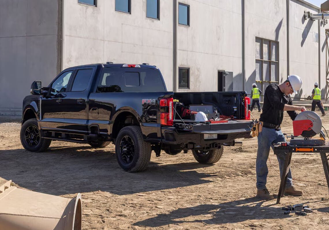Construction worker using the Ford Pickup to hold equipment while working